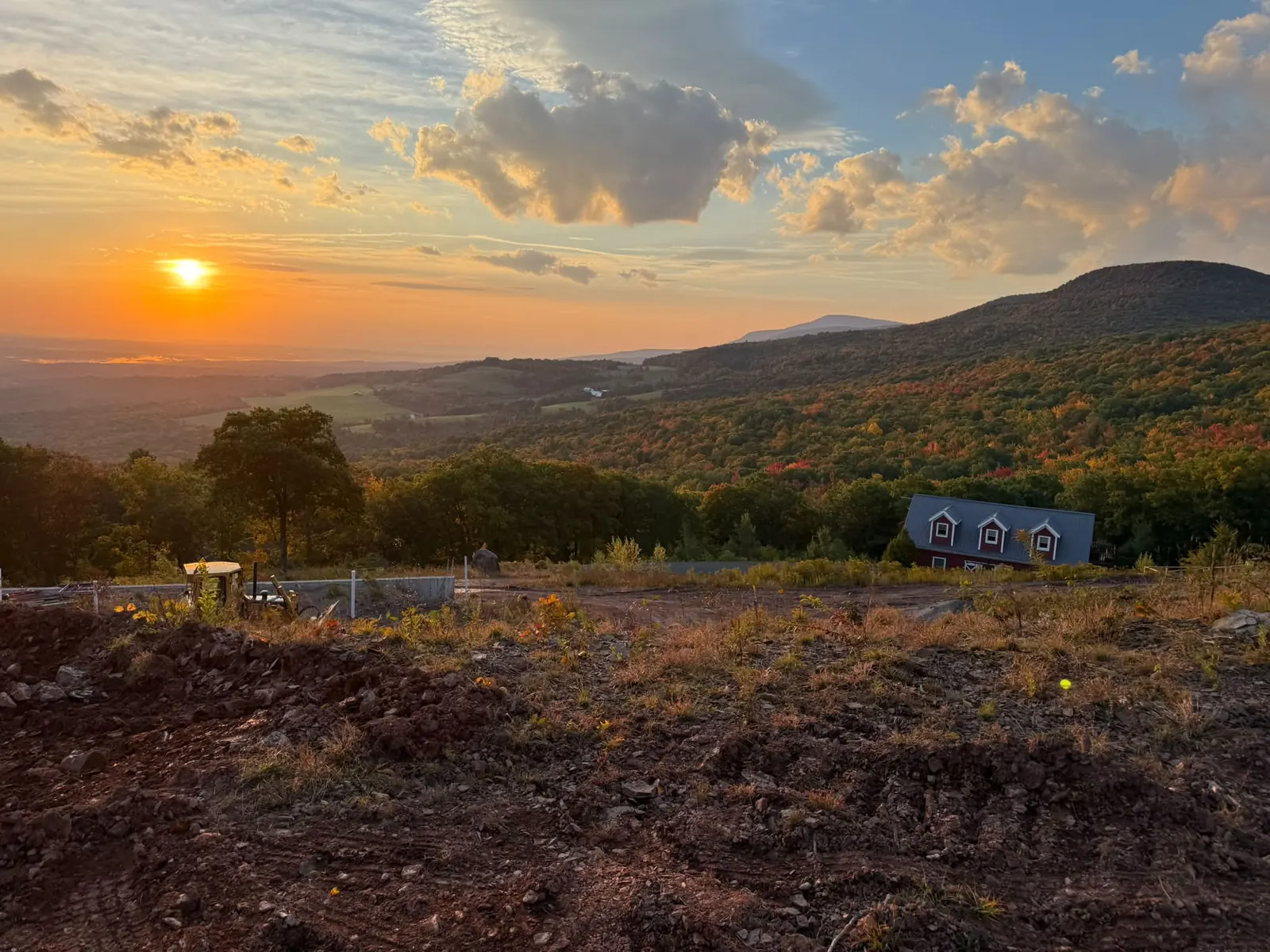 Hilltop job site at sunset with fall color across the mountains beyond