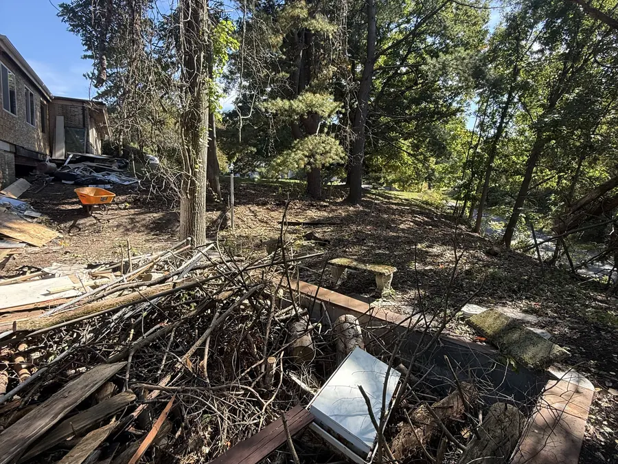 Building debris and old lumber piled under trees for hauling, demolition contractor cleanup