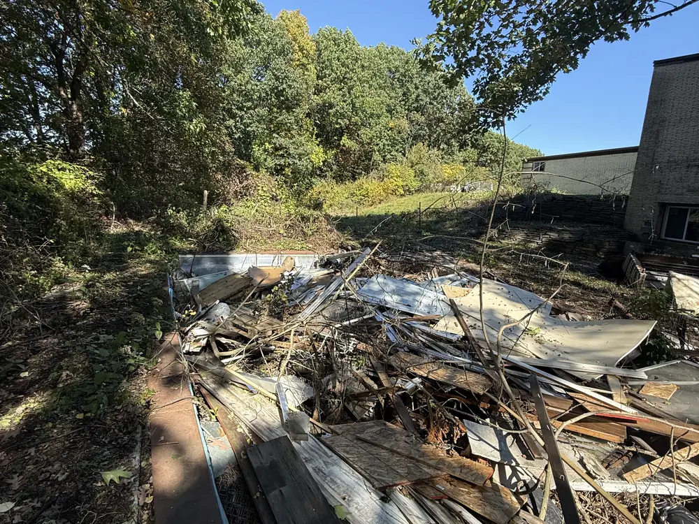 Pile of torn out lumber and building debris beside a house, demolition contractor cleanup
