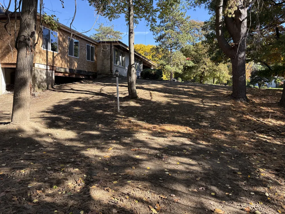 Front yard graded smooth up to a house under renovation after debris removal, demolition cleanup