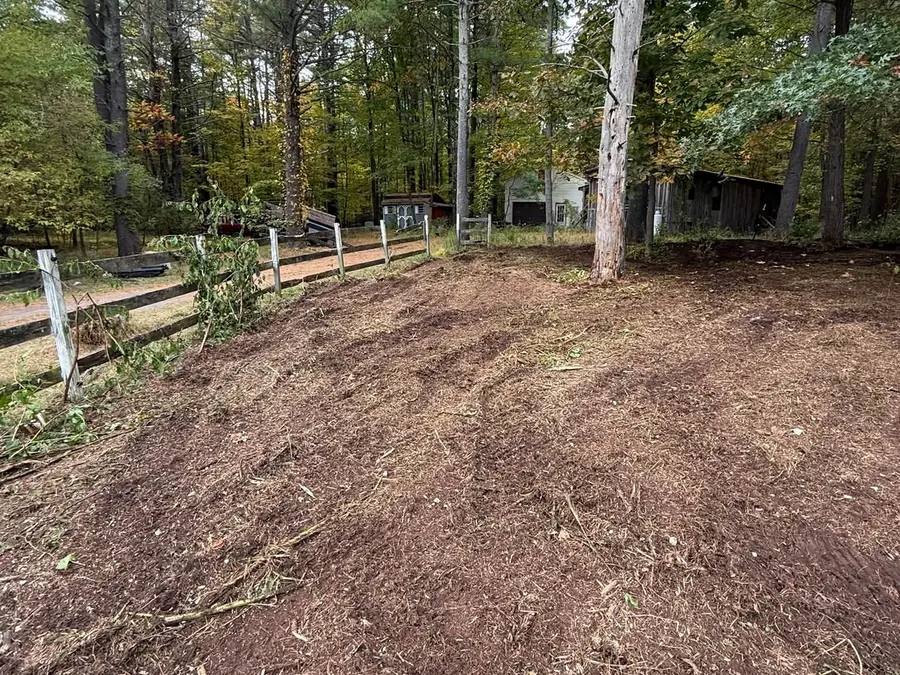 Ground covered in fresh mulch along a rail fence after forestry mulching of the brush