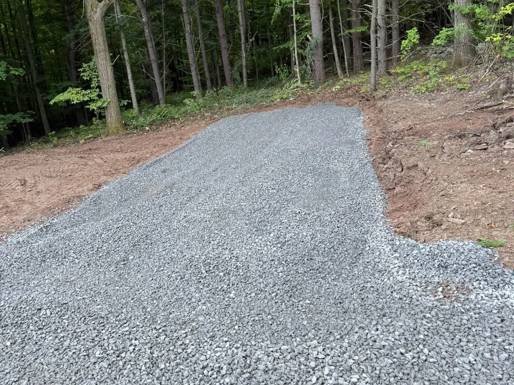 New gravel driveway pad of fresh crushed stone at the edge of the woods