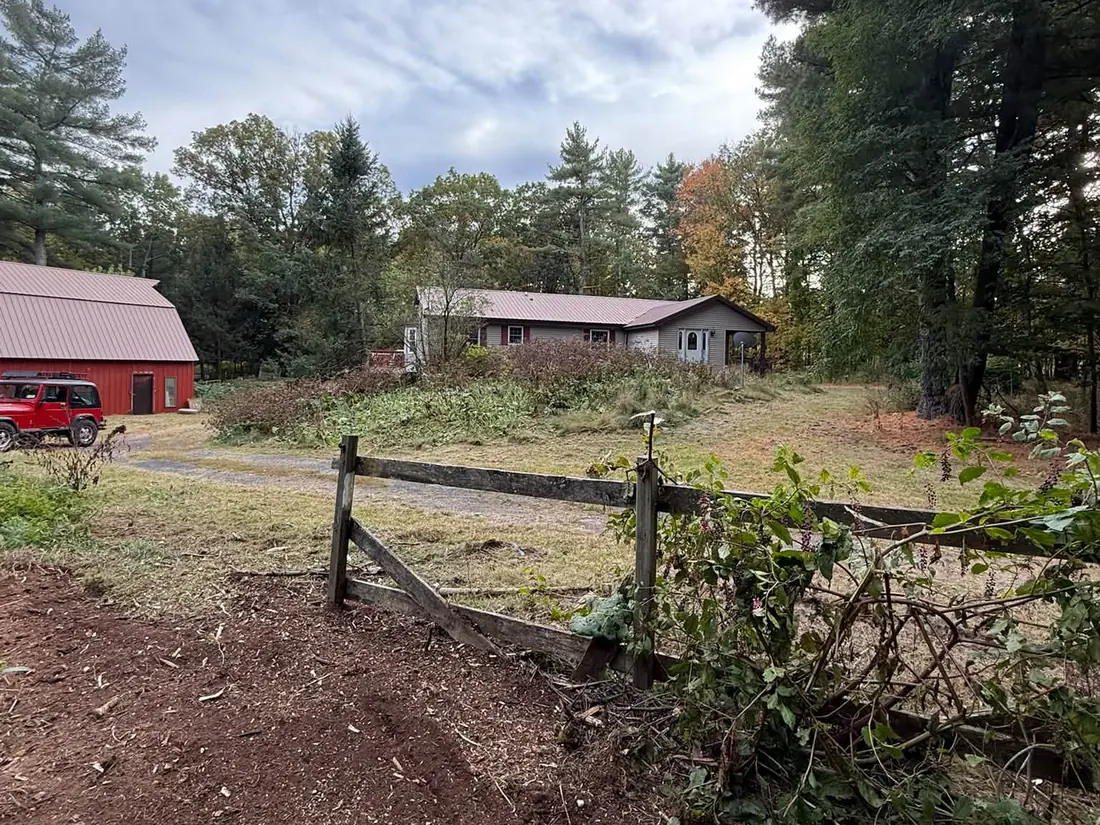 Fence line cleanup on a farm property with red barns, property maintenance