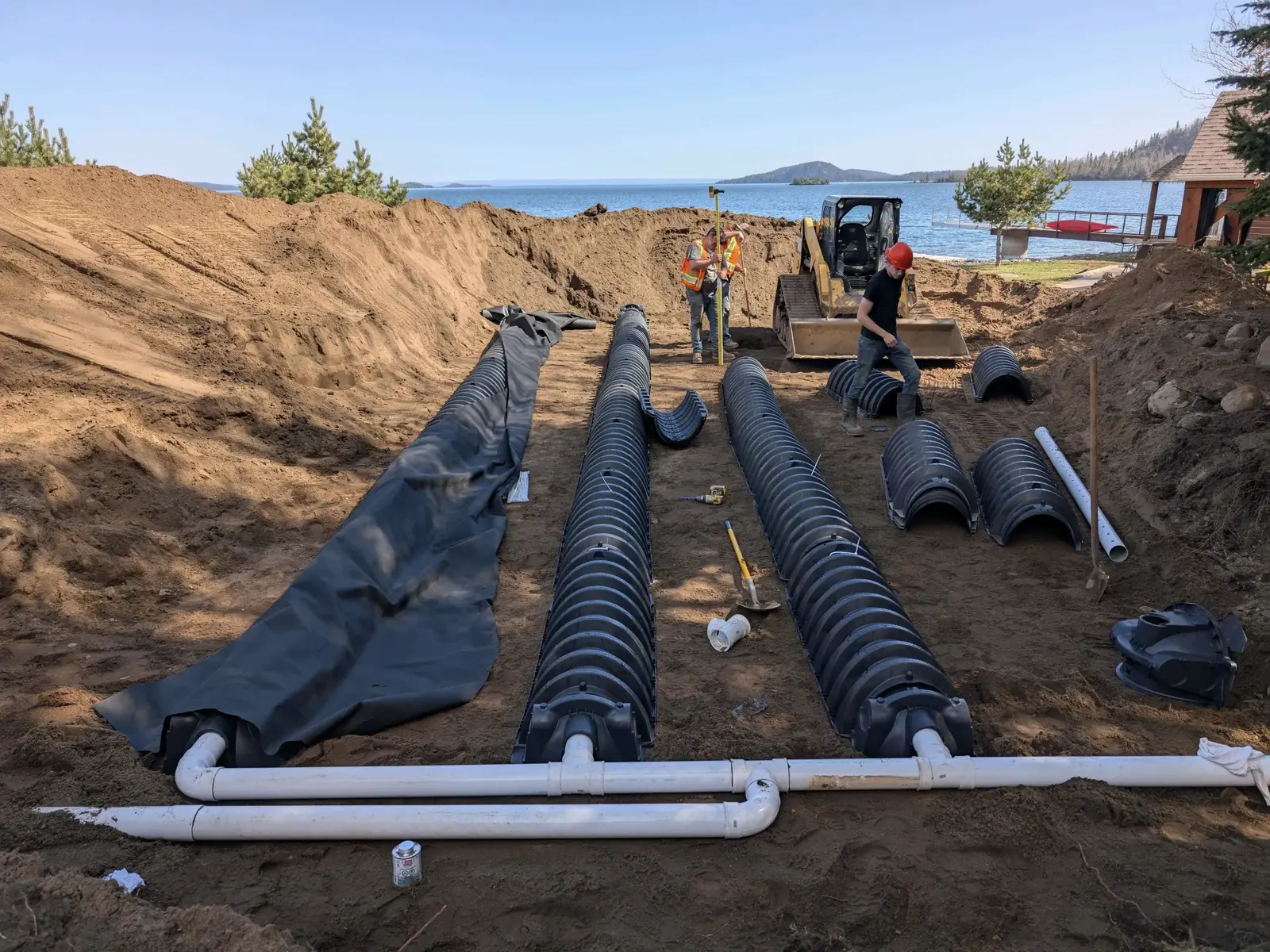 Leach field going in with rows of plastic leaching chambers on a pipe header in an open dig, septic system installation