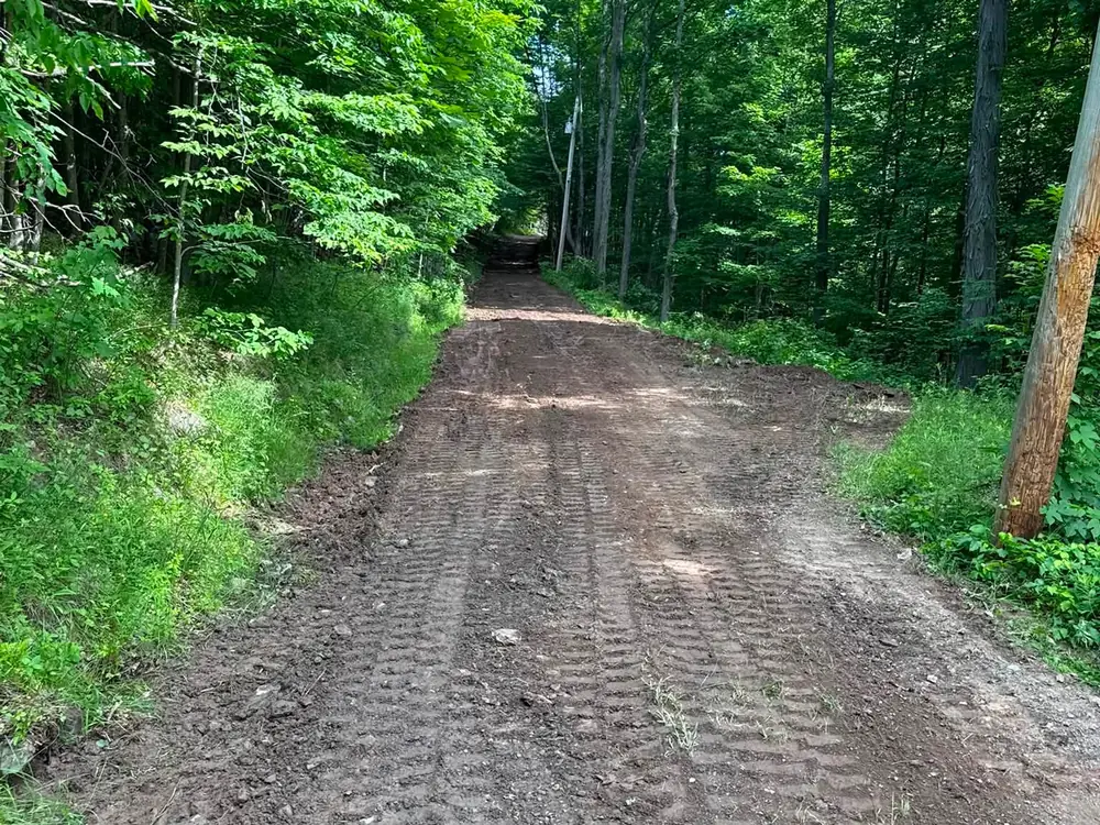 Rough graded access road cut through the woods, site preparation before stone