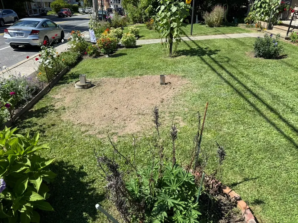 Two post sleeves set in fresh soil in a front lawn after post hole drilling, site preparation